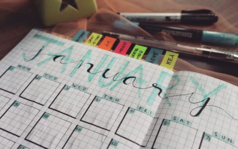 Handwritten January planner page with tags and pens on a desk. Perfect for organizing schedules.
