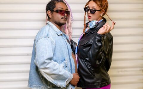 Fashionable couple wearing sunglasses, posing confidently in stylish denim and leather jackets.