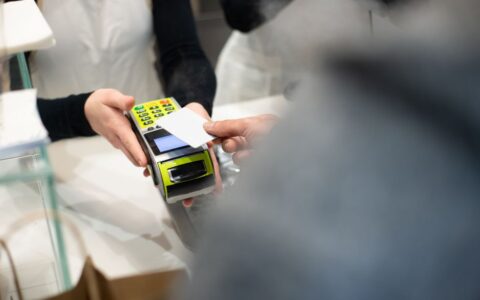 A customer pays with a card at a payment terminal in a modern retail store.
