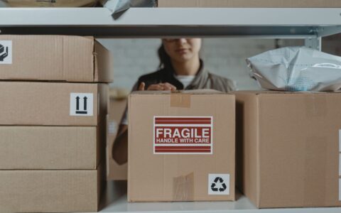 A person organizing fragile cardboard boxes in a warehouse setting.