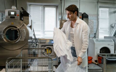Man organizing laundry in a modern industrial facility with large washing machines.