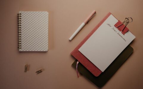 Organized flatlay of notebooks and pen for planning New Year's resolutions.