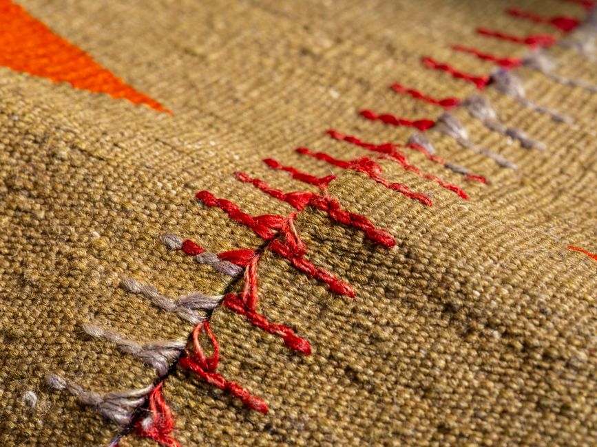 Detailed image showcasing the intricate texture and design of woven fabric with red stitching.