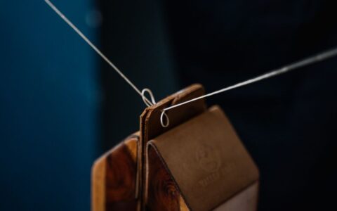 Detailed close-up of leather weights suspended on a wire, showcasing craftsmanship and material texture.