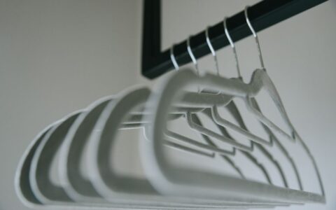 Close-up view of minimalist felt coat hangers on a clothes rack, showcasing simple design.