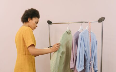 Woman checking clothing items on rack in boutique for inventory.